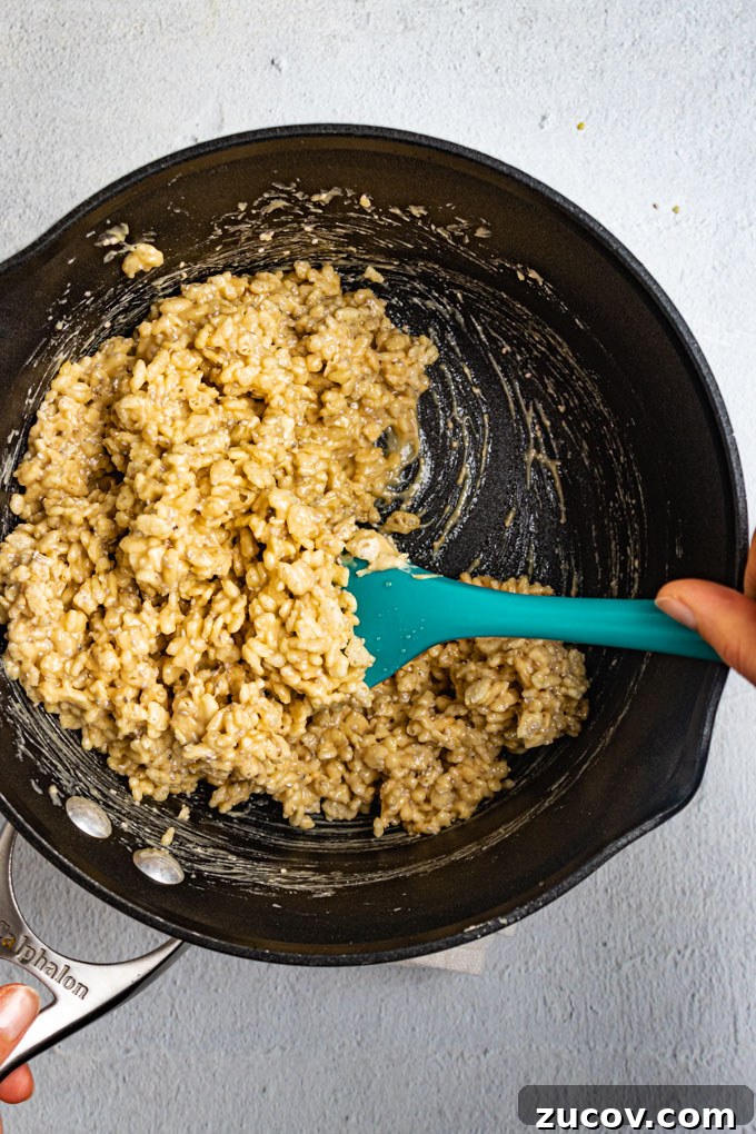Rice Krispie Treats Without Marshmallows – Chewy Almond Butter Bars 4 Rice cereal is being stirred into a cashew mixture in a sauce pot.