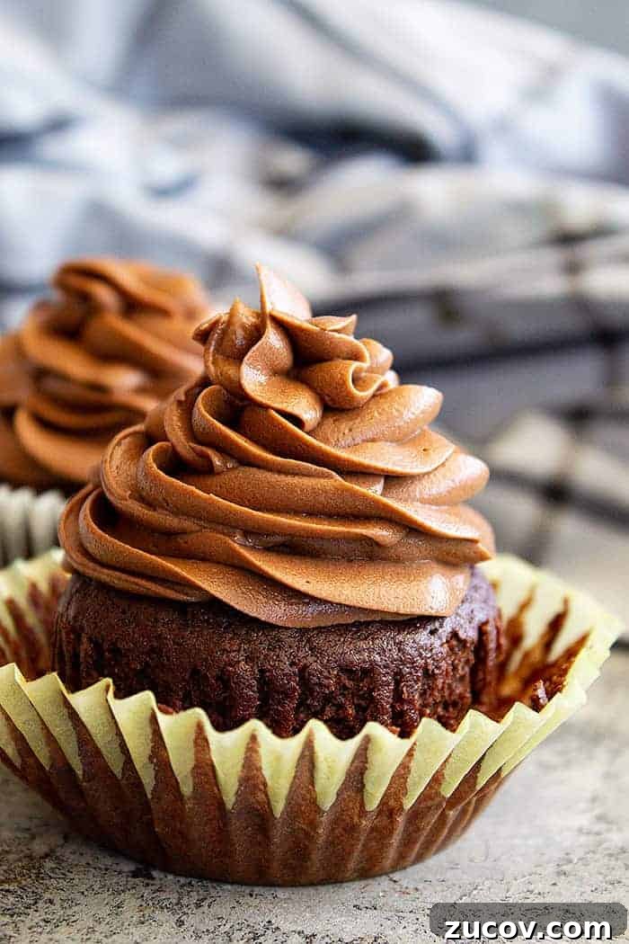 Decadent Chocolate Cream Cheese Frosting Recipe 5 closeup: chocolate cream cheese frosting piped in a swirl on top of a chocolate cupcake