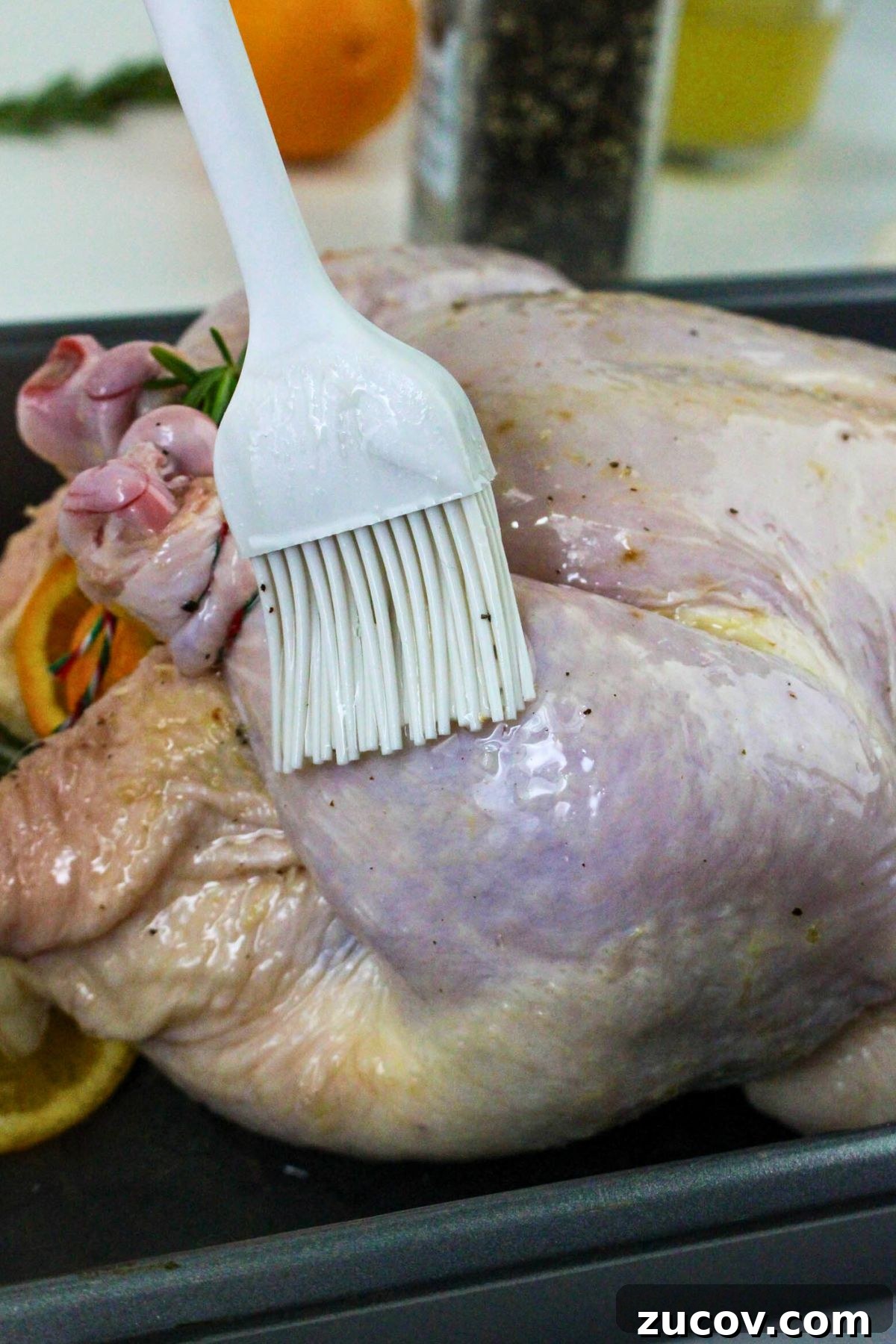 Succulent Roast Chicken Recipe for Christmas Dinner 6 Uncooked chicken being brushed with olive oil and then seasoned.