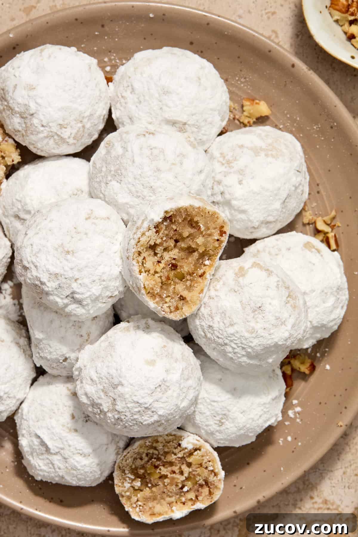 Cream Cheese Pecan Snowball Cookies for Christmas Baking 9 Cookies on plate with bite taken out of two separate cookies.