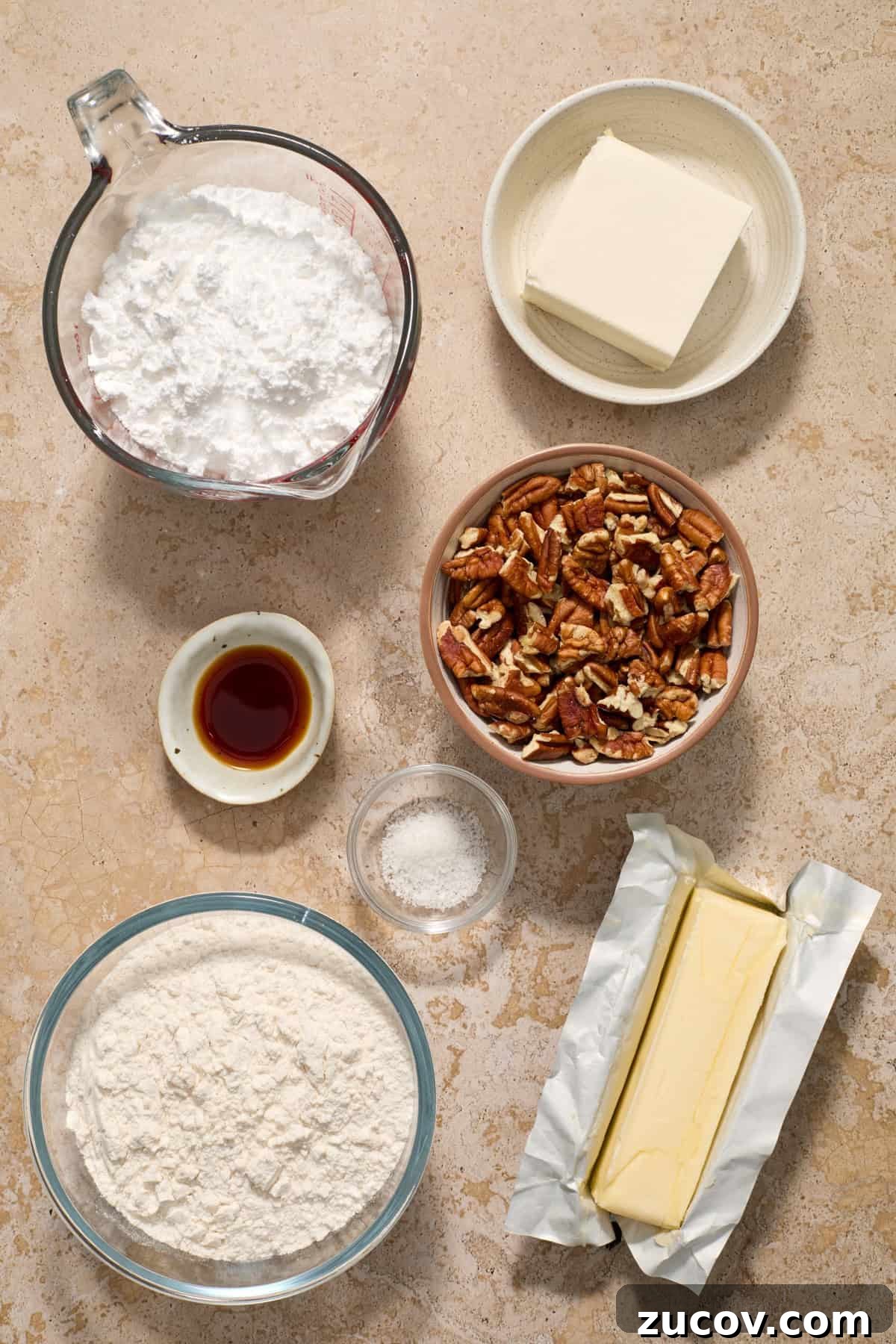 Cream Cheese Pecan Snowball Cookies for Christmas Baking 4 Butter, pecans, cream cheese, vanilla extract, flour and other ingredients arranged in bowls on surface.