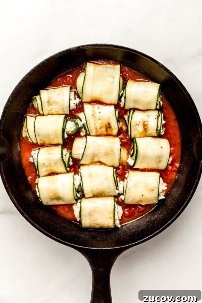 Ricotta-Stuffed Zucchini Roll-Ups with Tomato Basil Sauce 9 zucchini roll ups on tomato sauce in a cast iron skillet