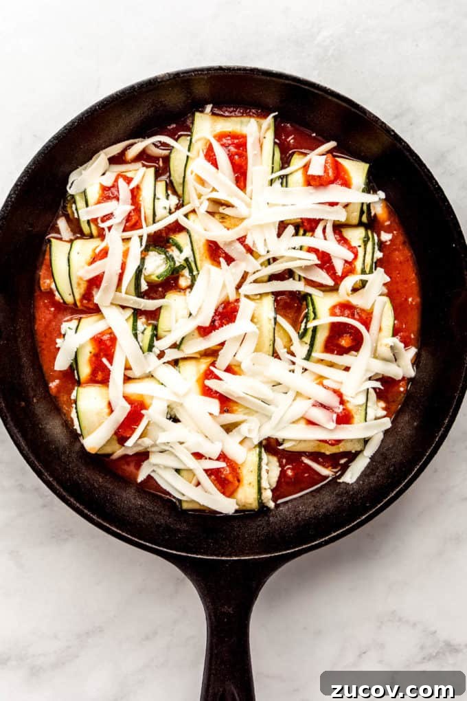 Ricotta-Stuffed Zucchini Roll-Ups with Tomato Basil Sauce 10 Zucchini roll ups topped with shredded cheese in a cast iron skillet