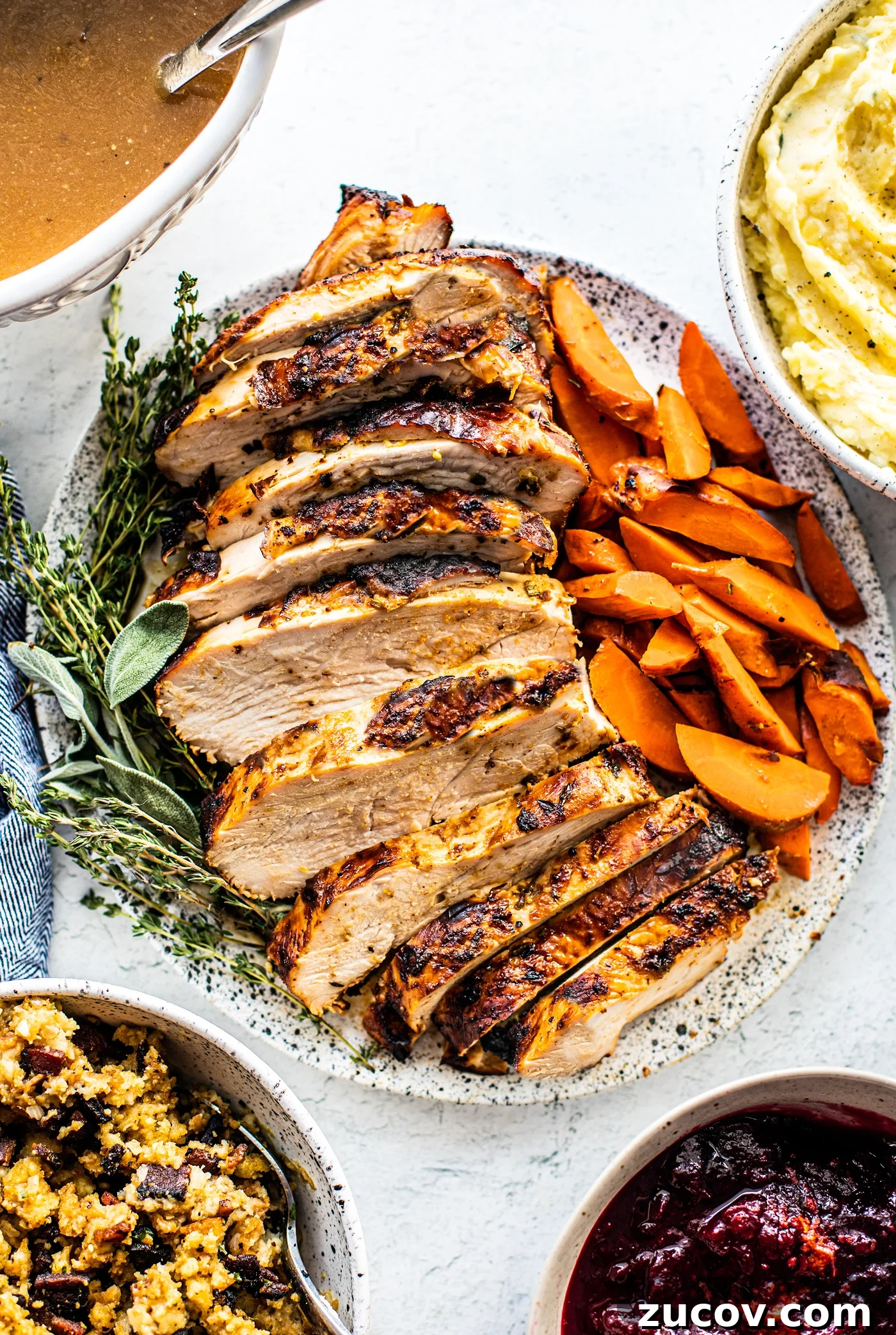 Crispy Juicy Air Fryer Turkey Breast Recipe 2 Sliced air fryer turkey breast on a serving platter with cooked carrots and fresh herbs.