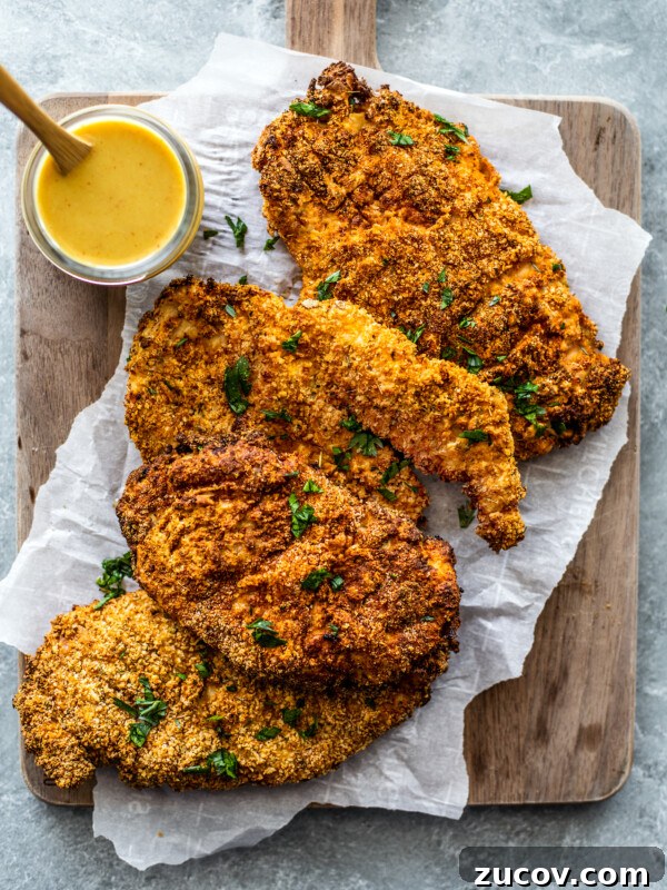 Crispy Juicy Air Fryer Turkey Breast Recipe 11 Wooden serving board with crispy chicken cutlets with honey mustard sauce on the side.