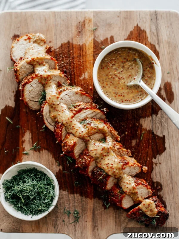 Crispy Juicy Air Fryer Turkey Breast Recipe 8 Sliced pork tenderloin on a wooden board drizzled with mustard sauce.
