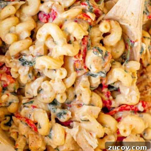Tuscan Chicken Macaroni and Cheese with Sun-Dried Tomatoes 5 A Tuscan chicken mac and cheese dish, complete with a wooden spoon.