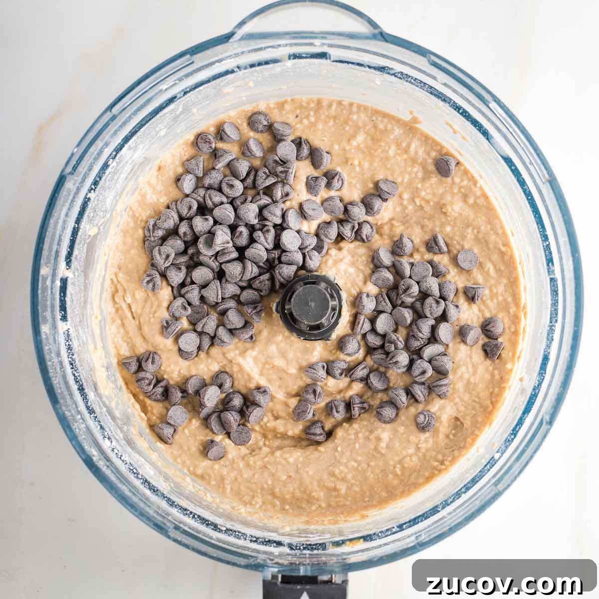 Vegan White Bean Blondies: Chewy, Protein-Packed Treats 9 Blondie batter in food processor bowl with chocolate chips on top.