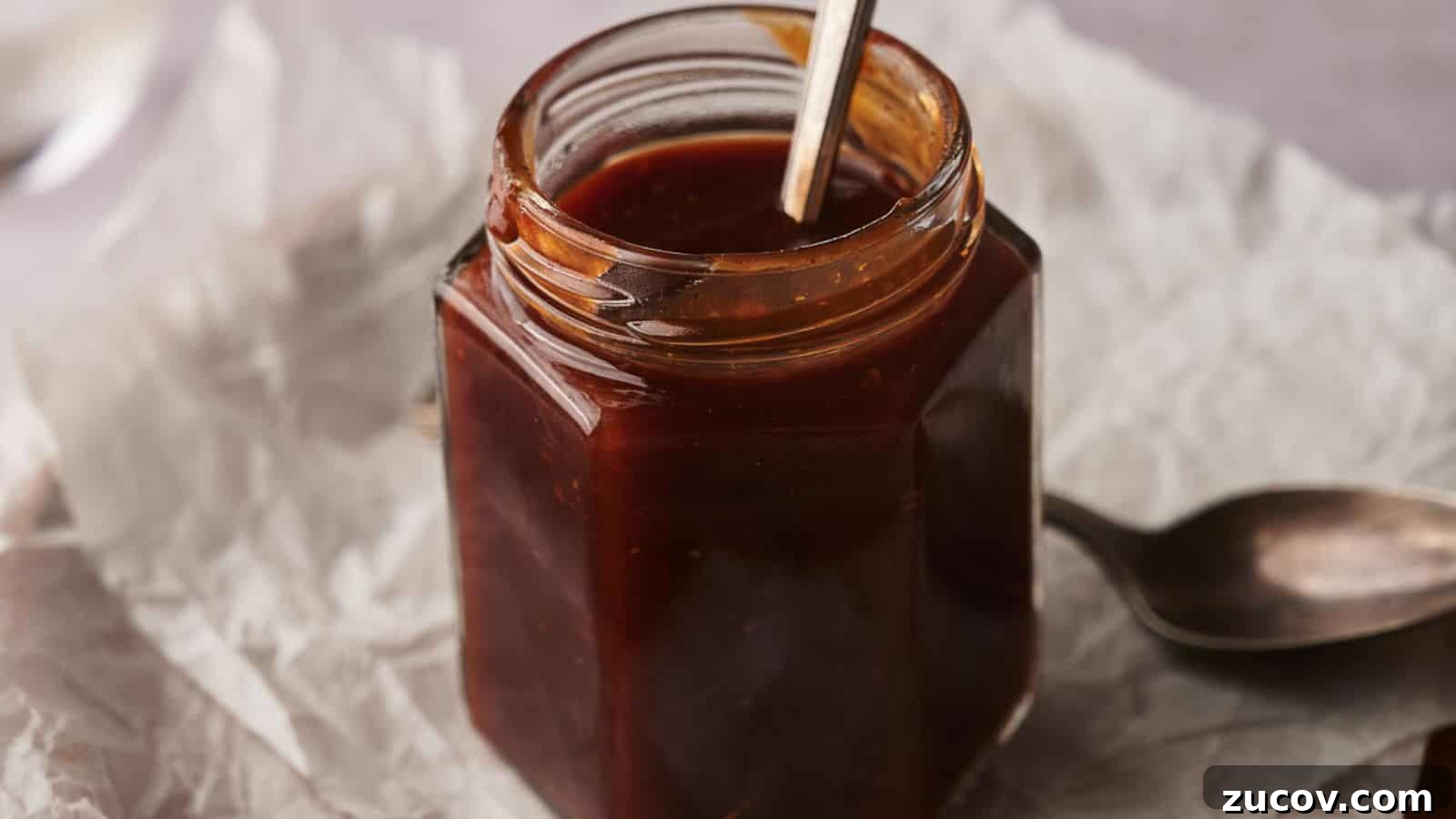 21 Summer Budget Meals That Make Takeout Obsolete 17 Homemade BBQ sauce in a jar with two spoons by the side.