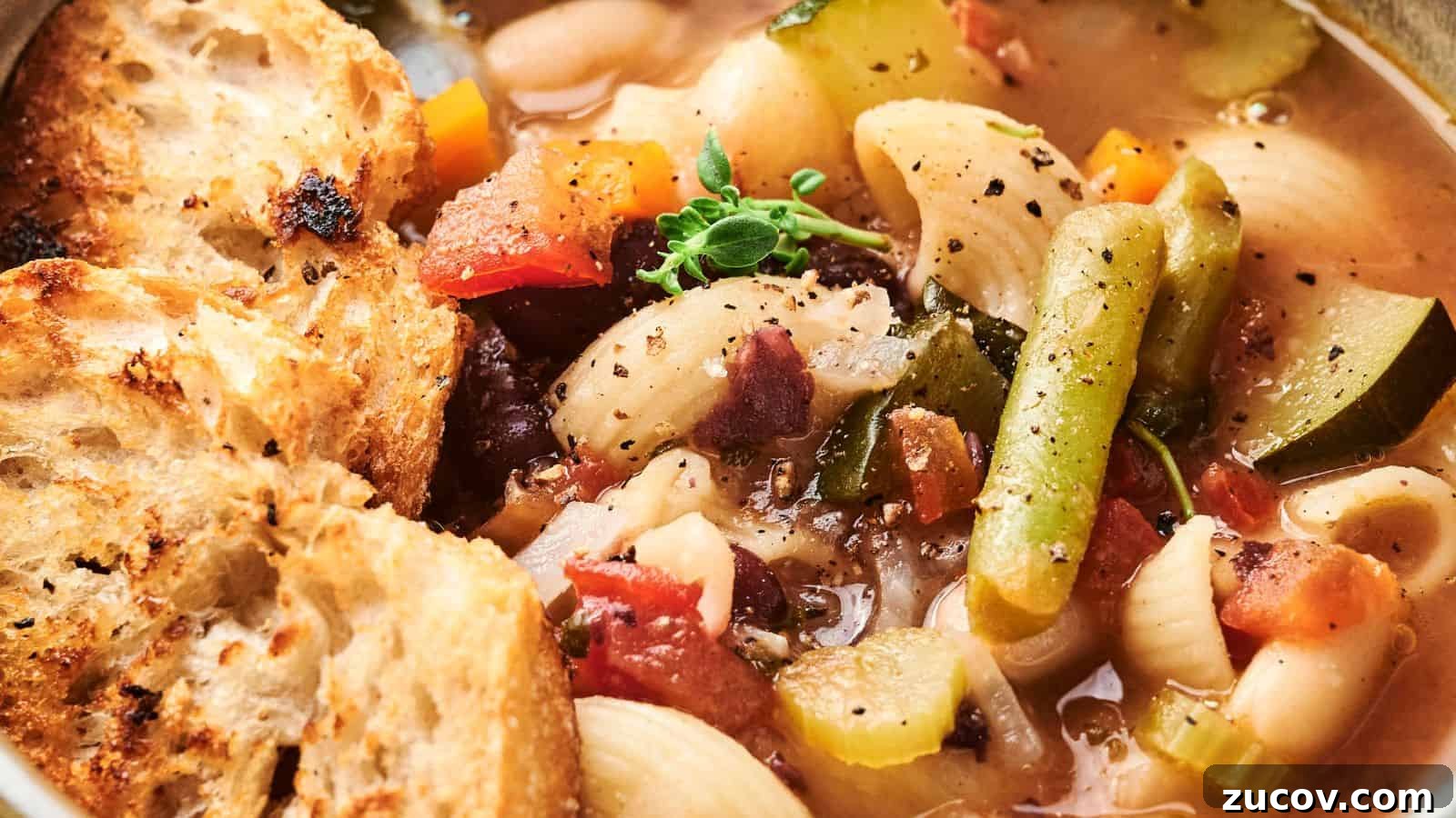21 Summer Budget Meals That Make Takeout Obsolete 22 A bowl of hearty minestrone soup packed with green beans, pasta, zucchini, tomatoes, and herbs, served with crusty bread slices.