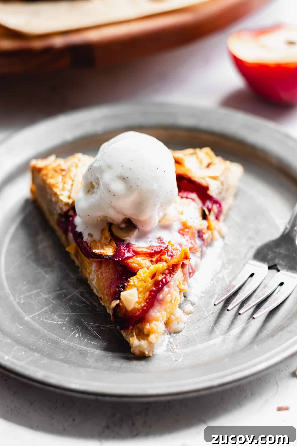 Peach and Almond Frangipane Galette Recipe 12 One slice of peach frangipane galette on a plate with a scoop of vanilla ice cream on top