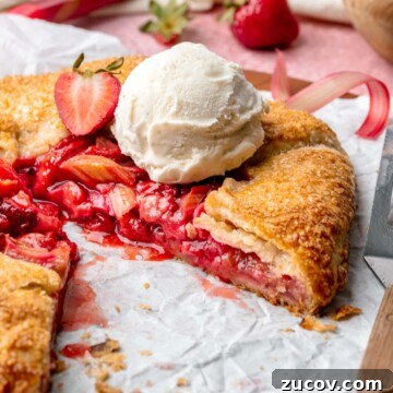 Sliced strawberry rhubarb galette with ice cream on top.
