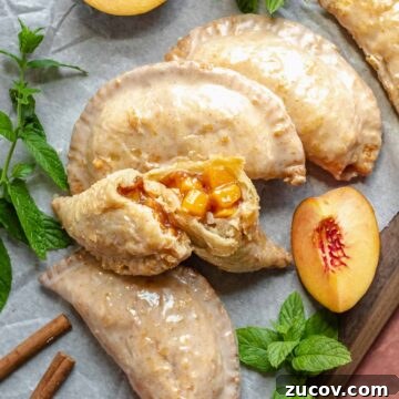 Fried peach pies on a board. One is broken open to expose the center filling.