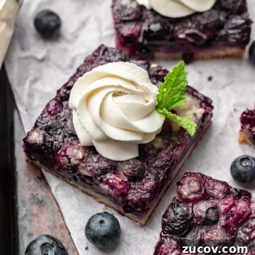 Blueberry pie bar squares with whipped cream and mint springs.