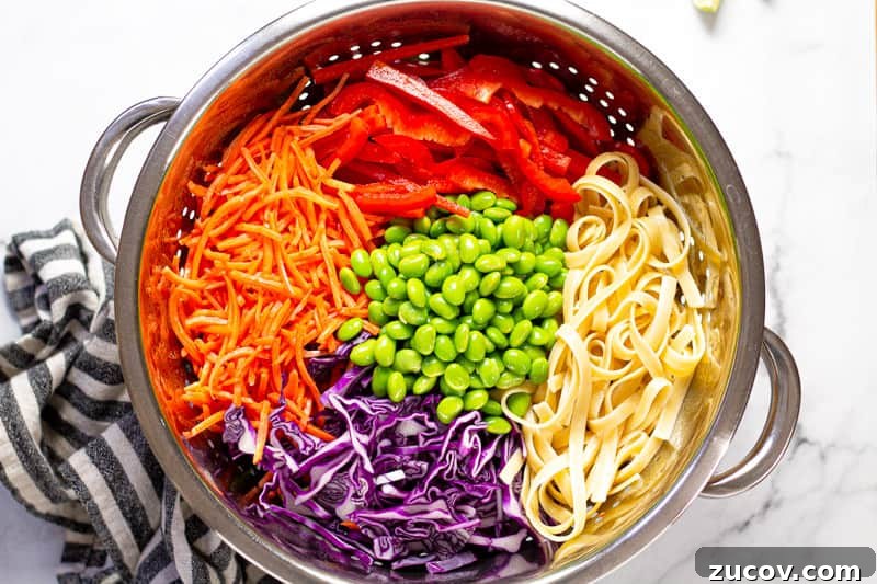 Chilled Vegan Peanut Noodle Salad with Crunchy Veggies 5 Metal strainer with ingredients to make Thai inspired peanut salad