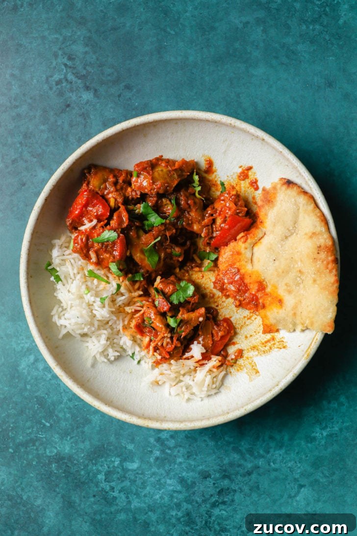 Authentic Chicken Jalfrezi Recipe: Spicy Tangy Curry at Home 12 Partially eaten Chicken Jalfrezi in a white bowl with rice and naan on the side