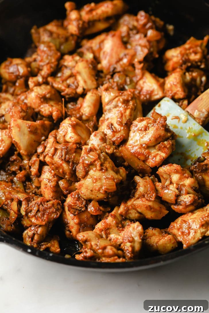 Authentic Chicken Jalfrezi Recipe: Spicy Tangy Curry at Home 8 Spices added to chicken thighs in a black skillet