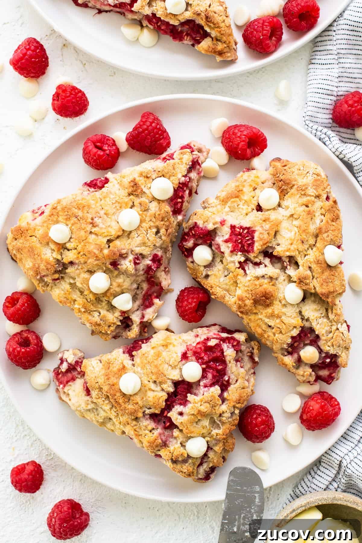 White Chocolate and Raspberry Scones Recipe for Brunch 2 Raspberries and white chocolate scones on a white plate.