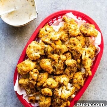 cauliflower nuggets in a red fry train with dipping sauce on the side