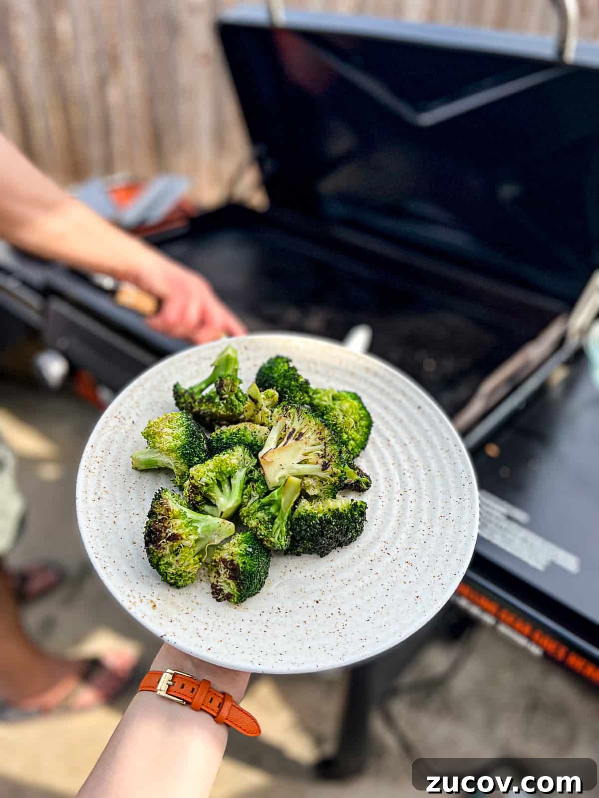 Griddled Broccoli: Crispy, Charred Broccoli on the Stovetop 3 Holding Griddled Broccoli Recipe in front of Traeger Flatrock Griddle Grill