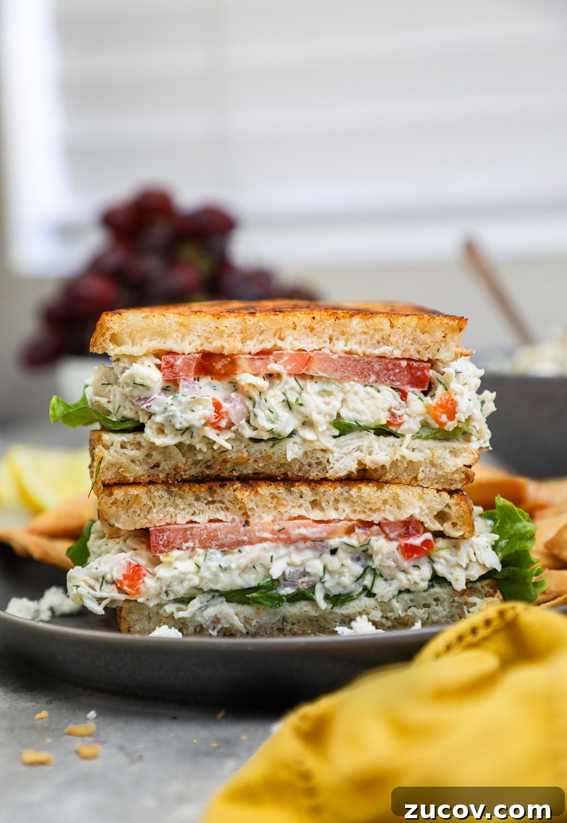 Greek-Style Feta Chicken Salad with Lemon-Dill Dressing 8 A feta chicken salad sandwich sitting next to a bowl of red grapes and pita chips