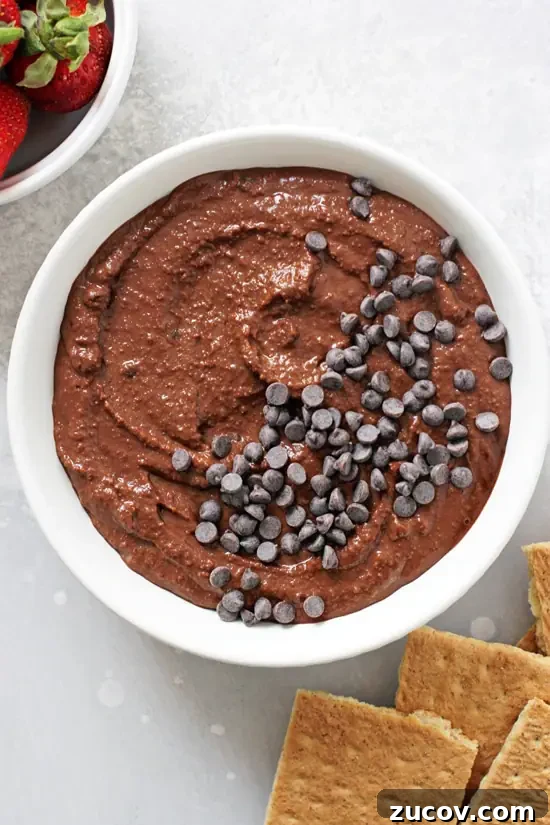 Just 10 minutes and a few pantry staples for this brownie batter dip. A white bowl filled with Brownie Batter Dip with graham crackers to the side.