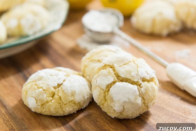 Chewy Lemon Crinkle Cookies Recipe for Bright Citrus Flavor 10 Lemon Crinkle Cookie Recipe - On A Wooden Board With Powdered Sugar Sprinkling Wand