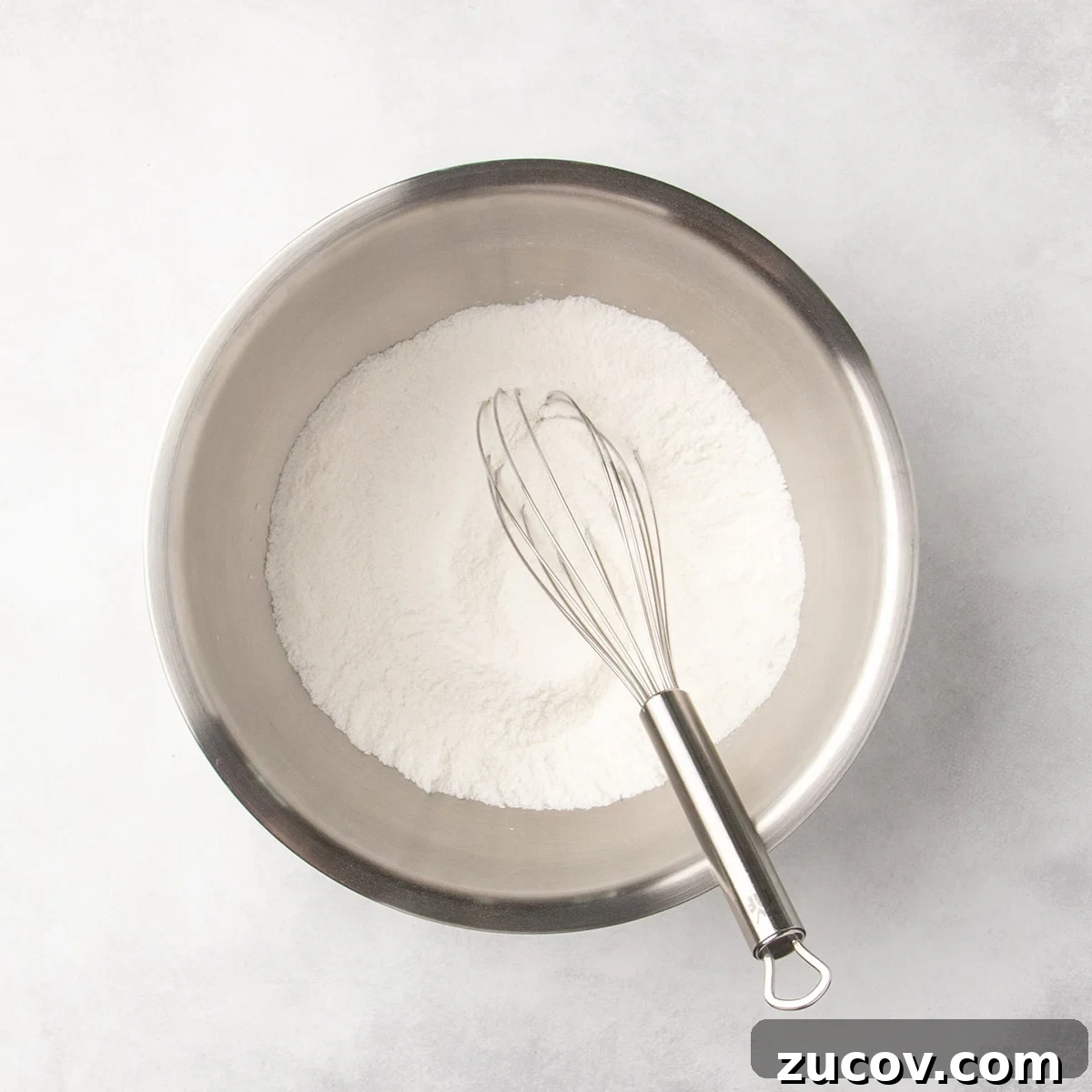 Gluten-Free Lemon Bar Recipe: Zesty, Tart Citrus Squares 12 Metal mixing bowl with white dry ingredients and a whisk resting inside.