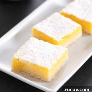 Gluten-Free Lemon Bar Recipe: Zesty, Tart Citrus Squares 20 3 bright yellow gluten free lemon bars with powdered sugar on top on a rectangular white platter