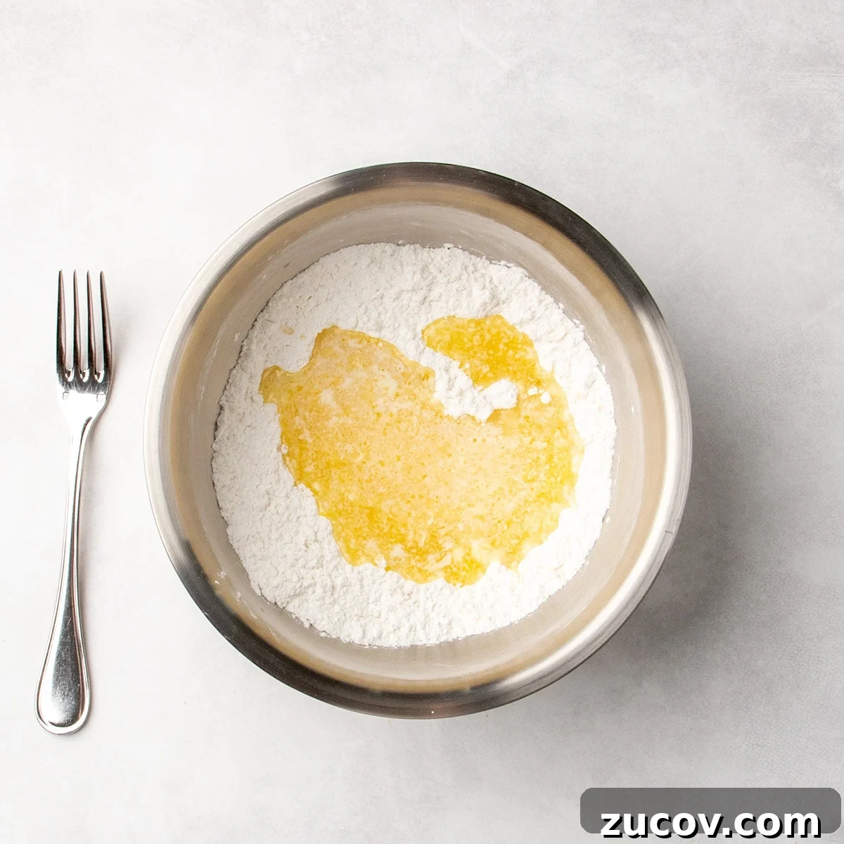 Gluten-Free Lemon Bar Recipe: Zesty, Tart Citrus Squares 7 Melted butter mixture poured over white dry ingredients in a metal mixing bowl.