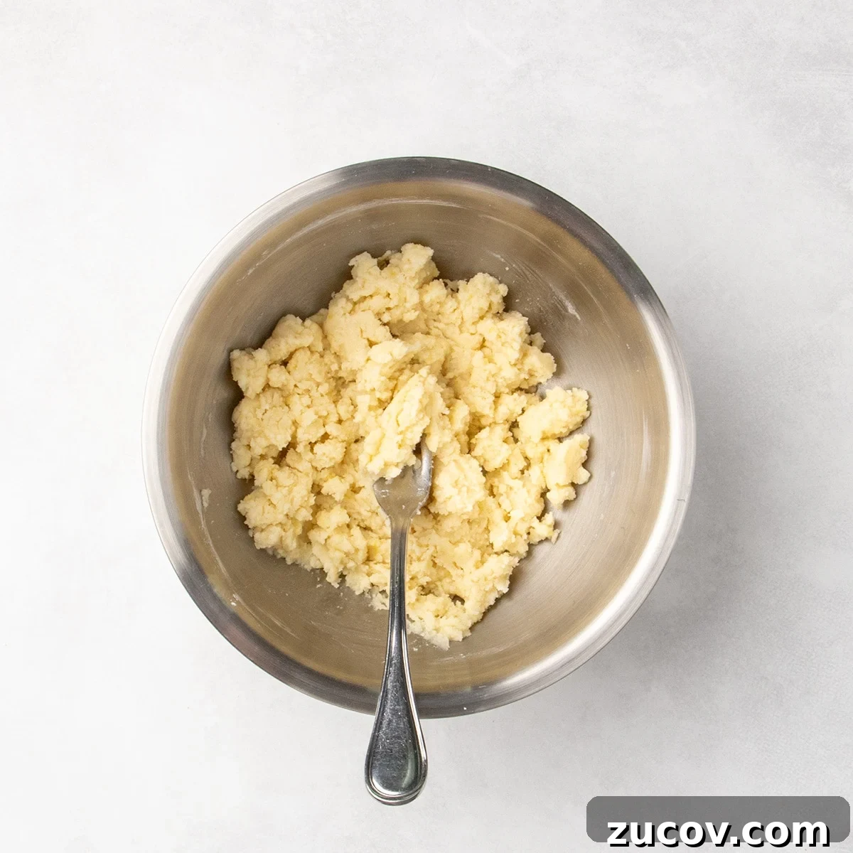 Gluten-Free Lemon Bar Recipe: Zesty, Tart Citrus Squares 8 Clumpy pale dough mixture in a metal bowl with a fork.