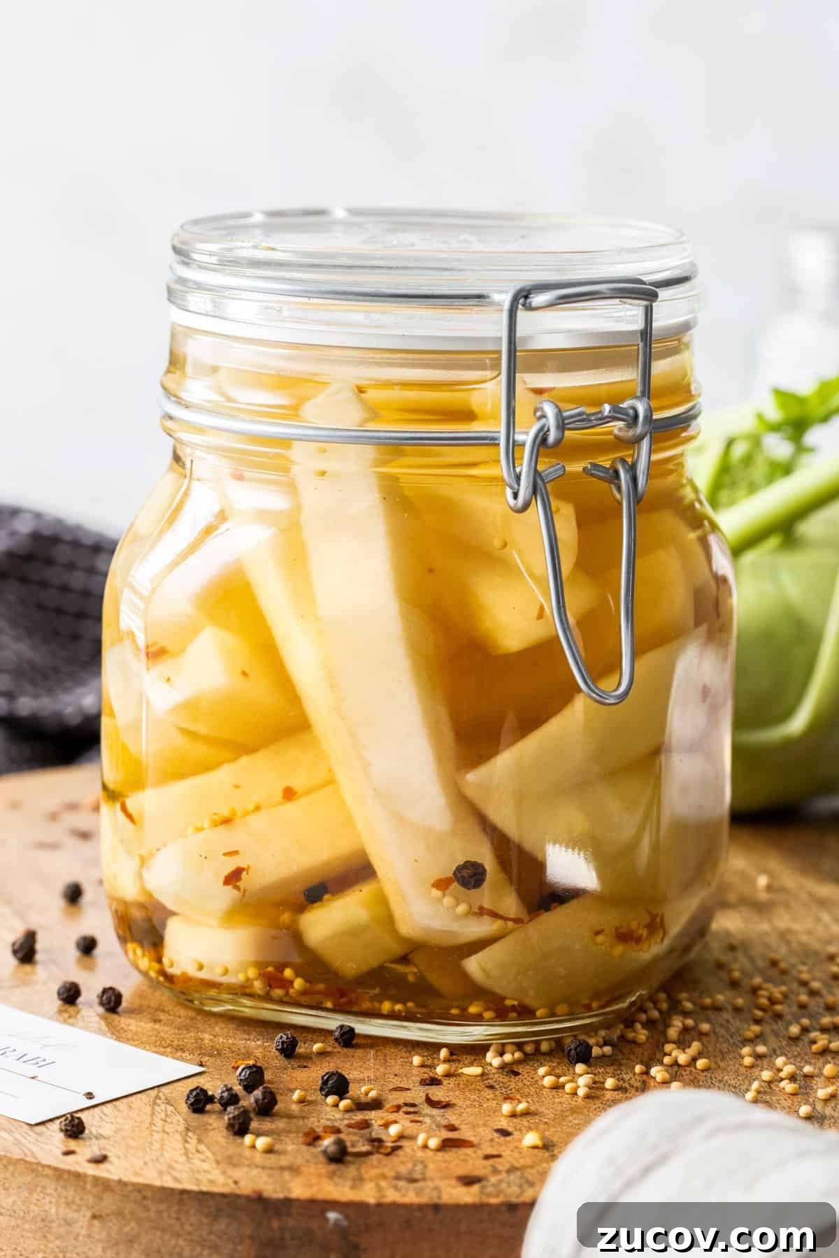 Crispy Pickled Kohlrabi Recipe for Tangy, Quick Ferments 2 Jar of Pickled Kohlrabi, sitting on a round wooden board, with some herbs and spices around the edge.