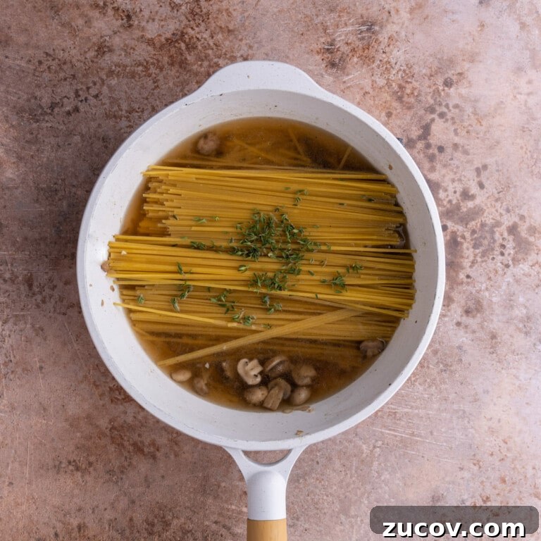 20-Minute Mushroom Marsala Pasta Recipe (Vegetarian) 11 Pasta submerged in vegetable broth and Marsala cooking wine in a saucepan