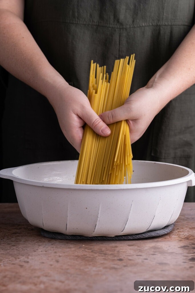 20-Minute Mushroom Marsala Pasta Recipe (Vegetarian) 6 Adding Fettuccine to a large saucepan to cook in vegetable broth and Marsala cooking wine