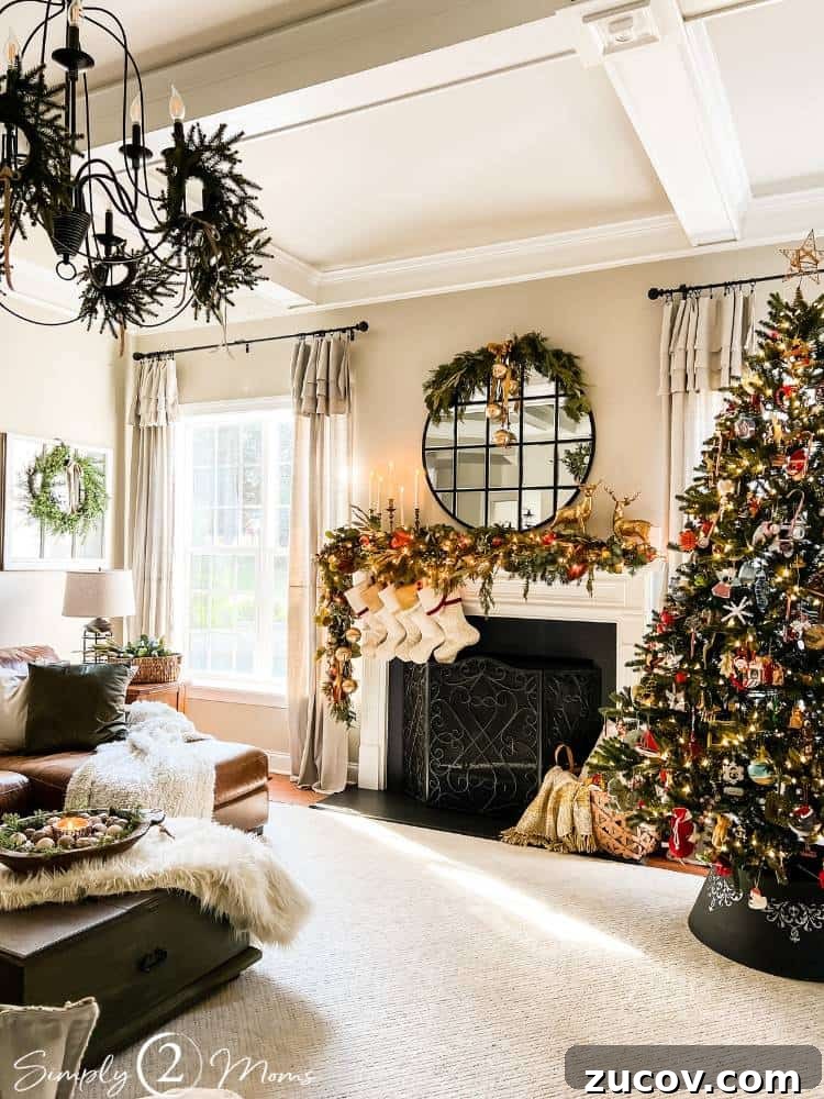 13 Elegant Christmas Fireplace Decorating Ideas to Try This Year 2 Family room decorated for Christmas with a tree, fireplace with greenery, mirror, and wreaths.