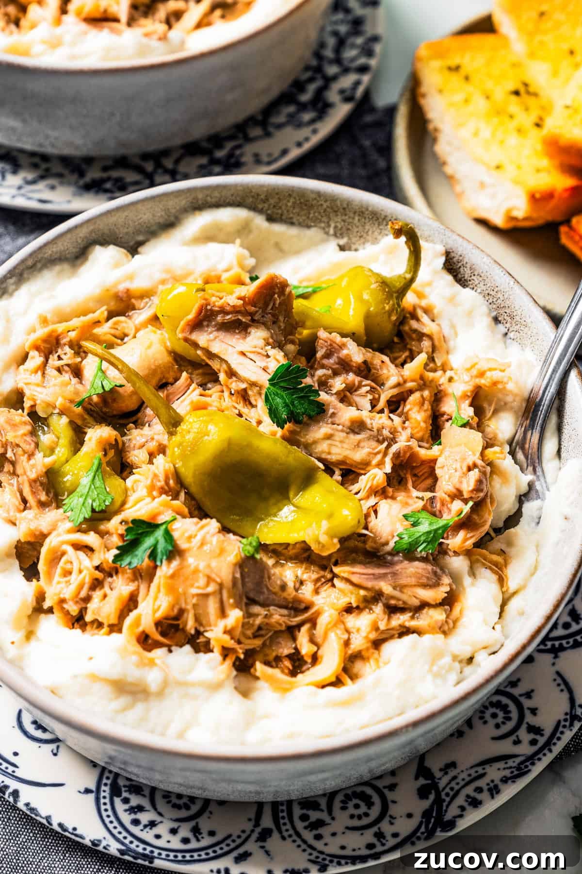 Mississippi chicken is an easy crock pot recipe with juicy chicken shredded in savory pepperoncini ranch sauce. Make it with 5 ingredients! Mississippi chicken served over a bowl of mashed potatoes.