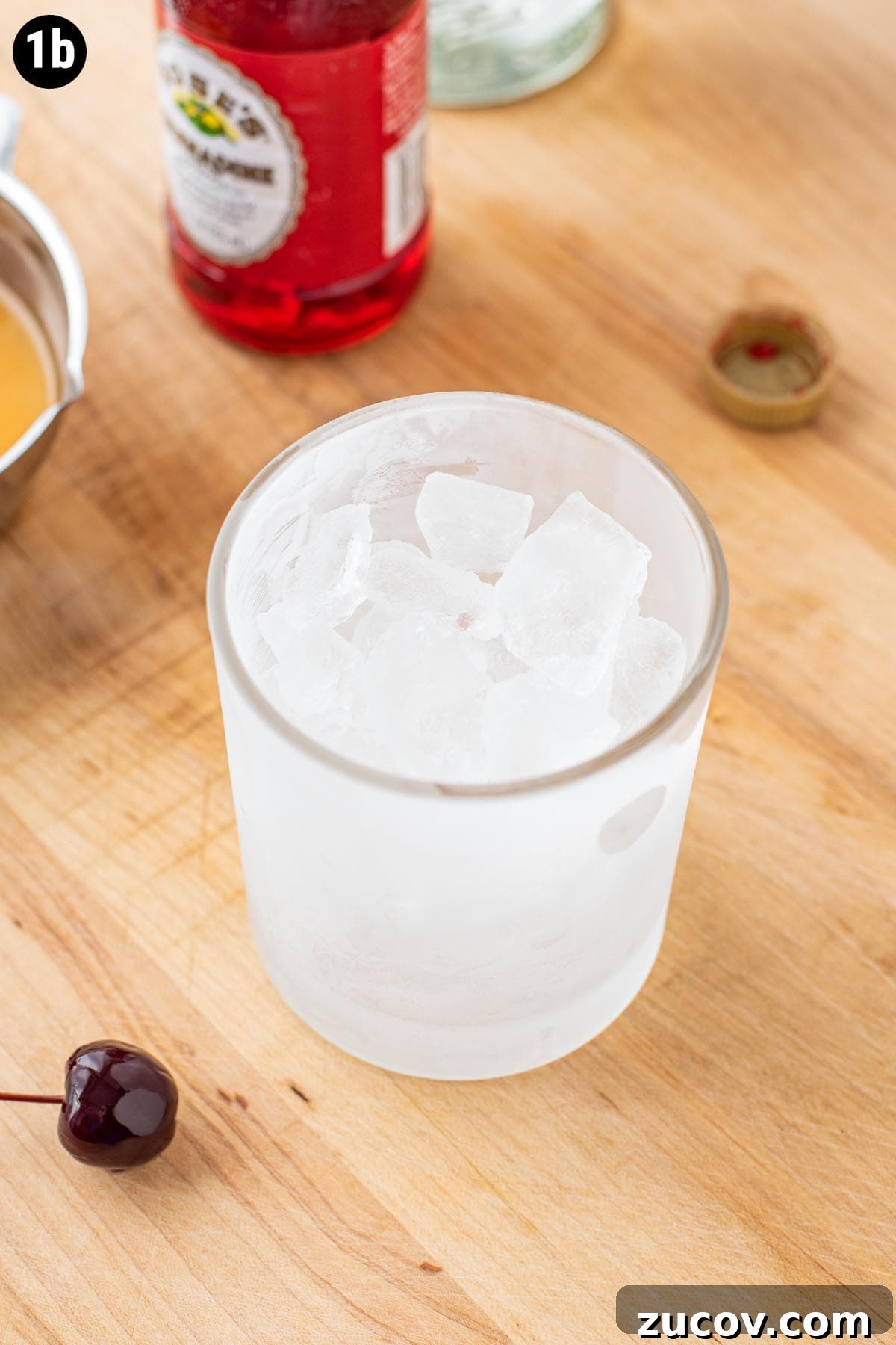 Tequila Sunrise Cocktail Recipe: Ingredients, Tips & Variations 5 A frozen double old fashioned glass on a wooden cutting board filled with ice.