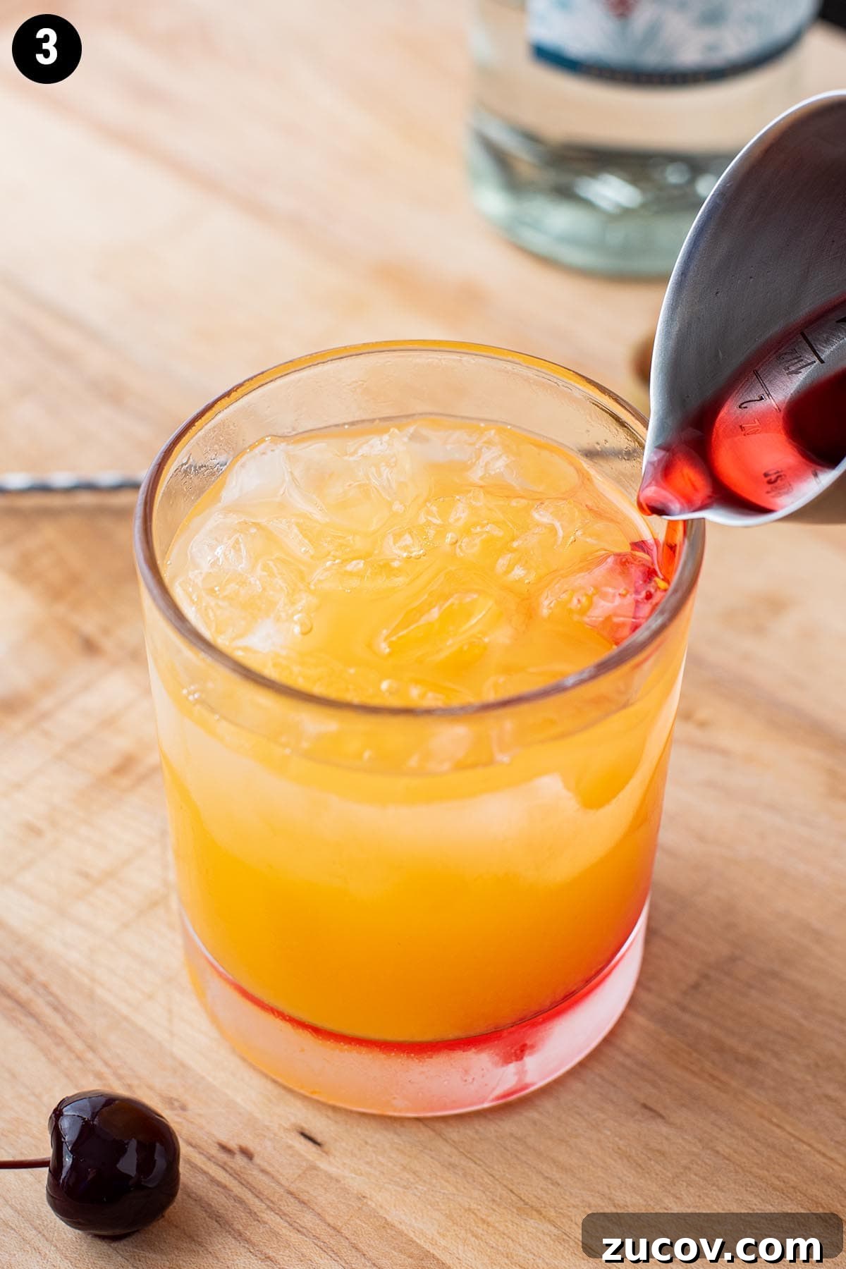 Tequila Sunrise Cocktail Recipe: Ingredients, Tips & Variations 8 Adding grenadine to a Tequila Sunrise with a cocktail jigger.