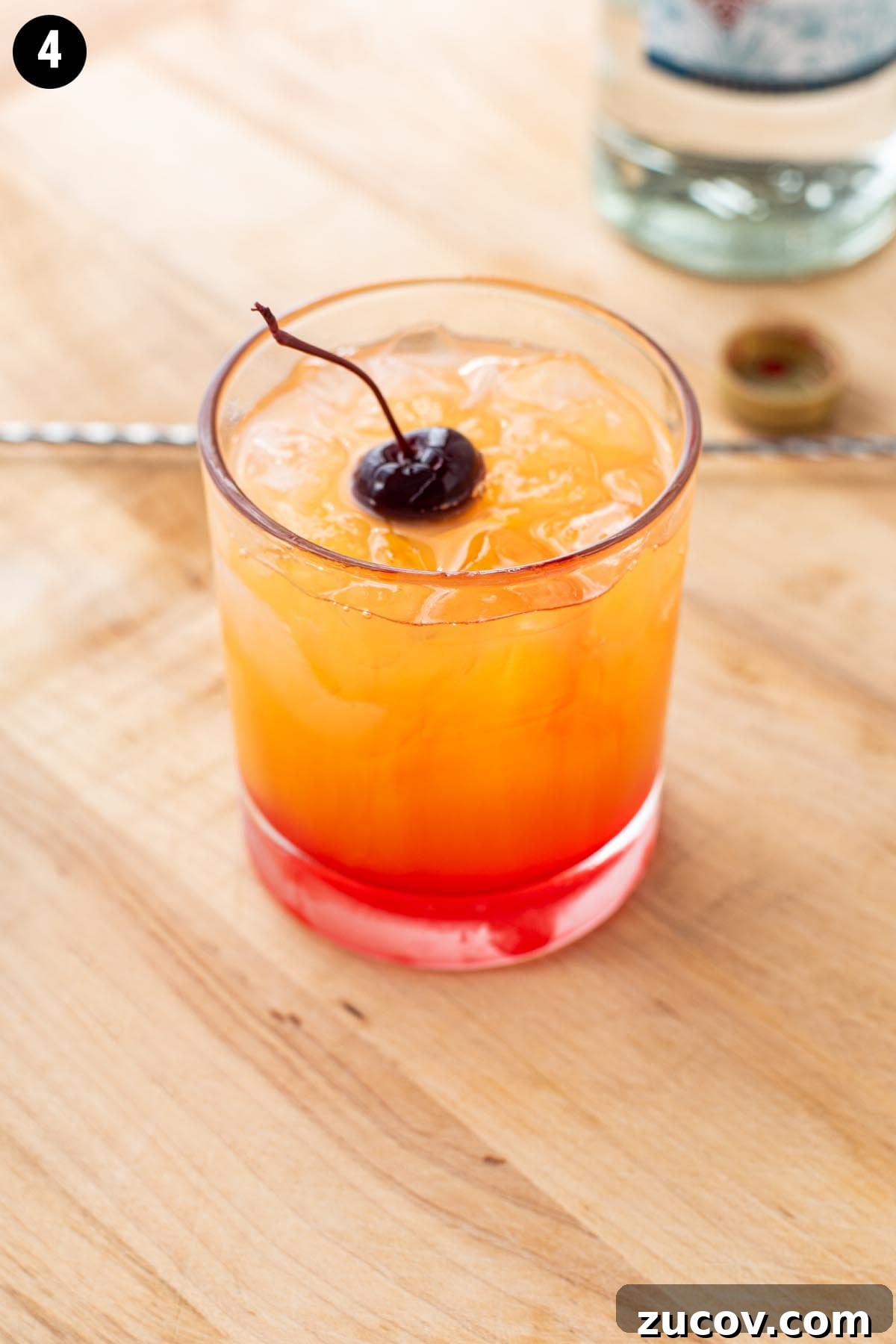Tequila Sunrise Cocktail Recipe: Ingredients, Tips & Variations 9 A golden Tequila Sunrise cocktail garnished with a brandied cherry.
