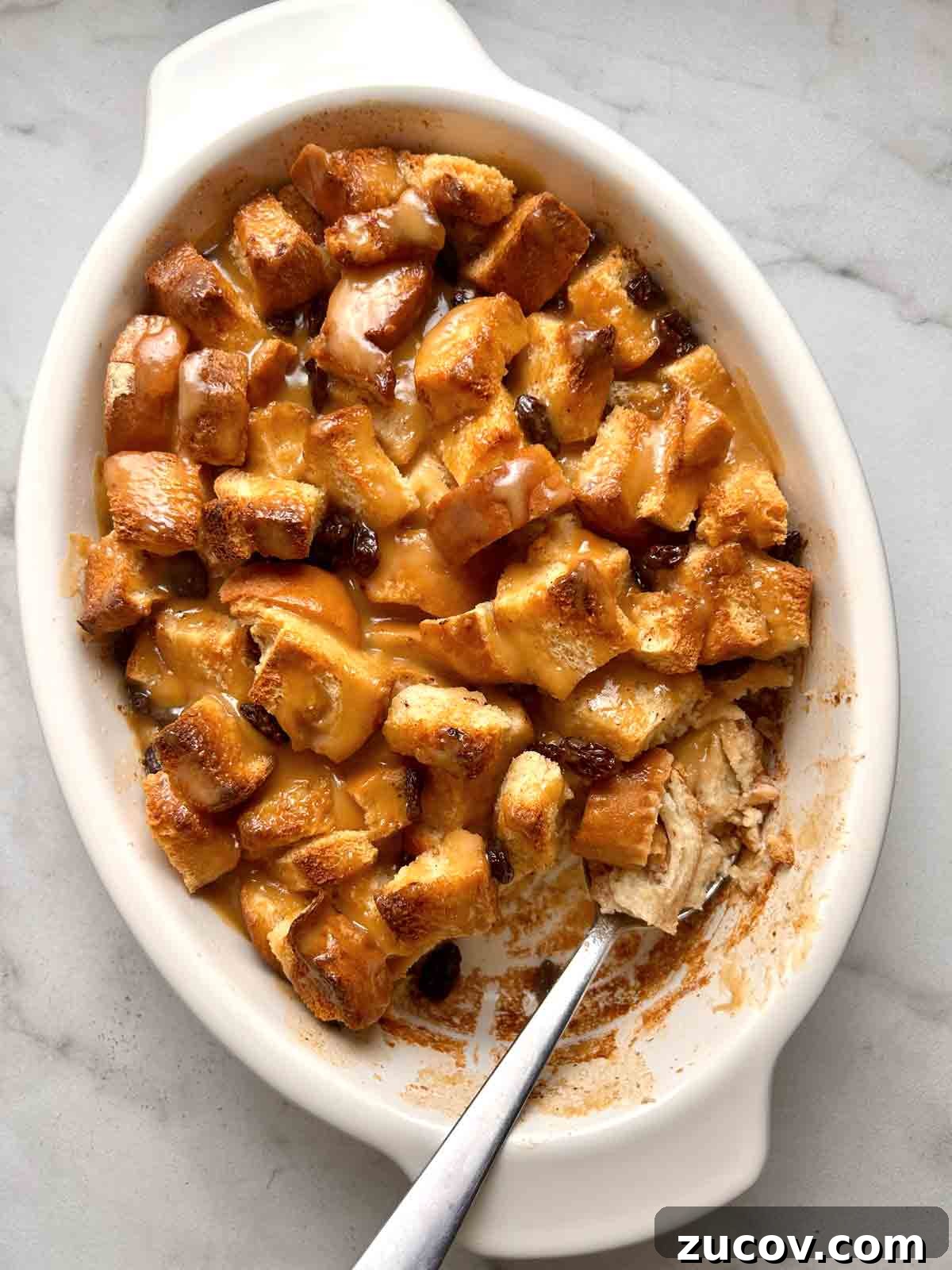 Classic Bread Pudding Recipe with Caramel Sauce and Vanilla 7 finished bread pudding with portion scooped out of it in baking dish.