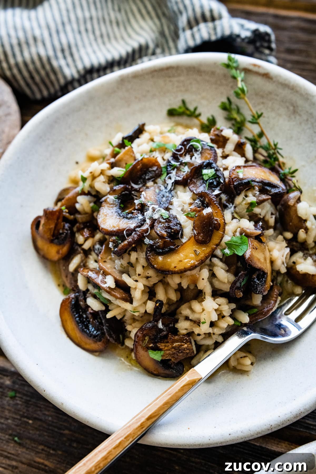 Orzo vs Risotto: Key Differences, Cooking Tips & Recipes 7 close up of plated mushroom risotto in a white bowl with a fork in the bowl.