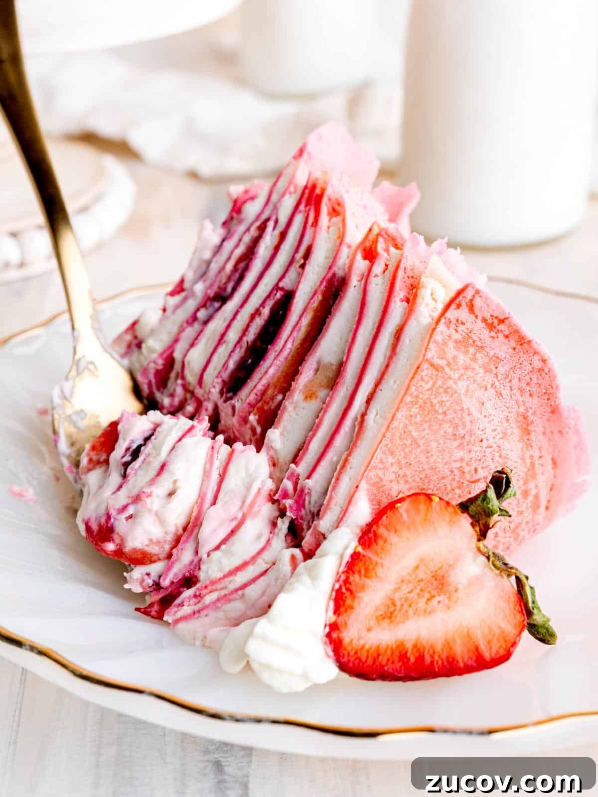 Strawberry & Cream Layered Crepe Cake Recipe 6 A slice of strawberry crepe cake sitting on a plate with a fork.