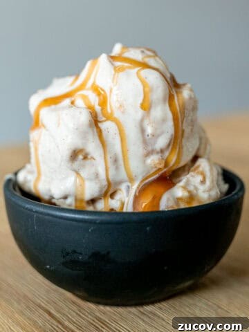 Apple cheesecake ice cream in a bowl with caramel sauce drizzled on top.