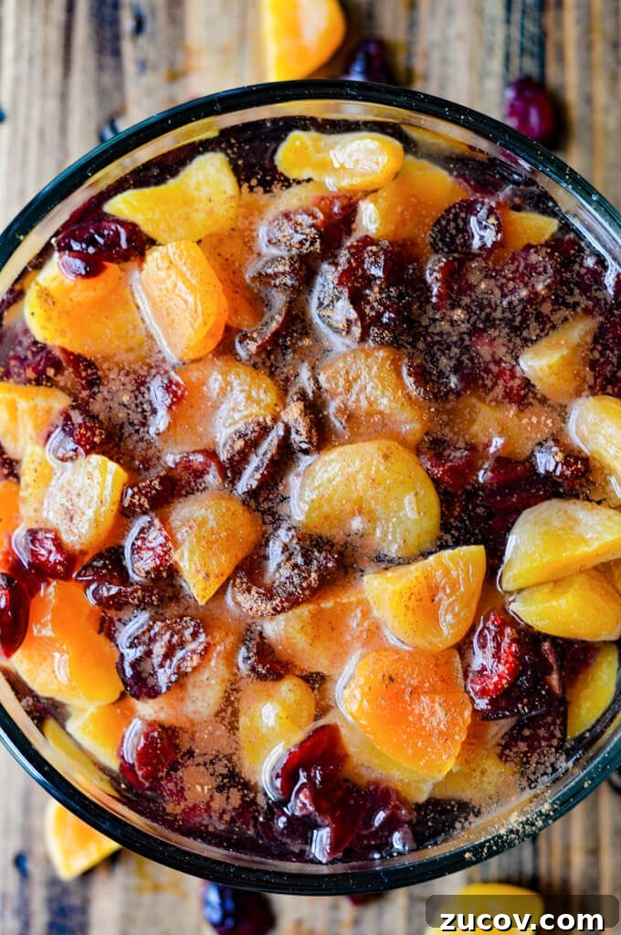 Fruit-Stuffed Pork Loin Roast with Apple and Cranberry Filling 3 A clear glass bowl of dried apricots and craisins soaking in water with cinnamon sprinkled on top.