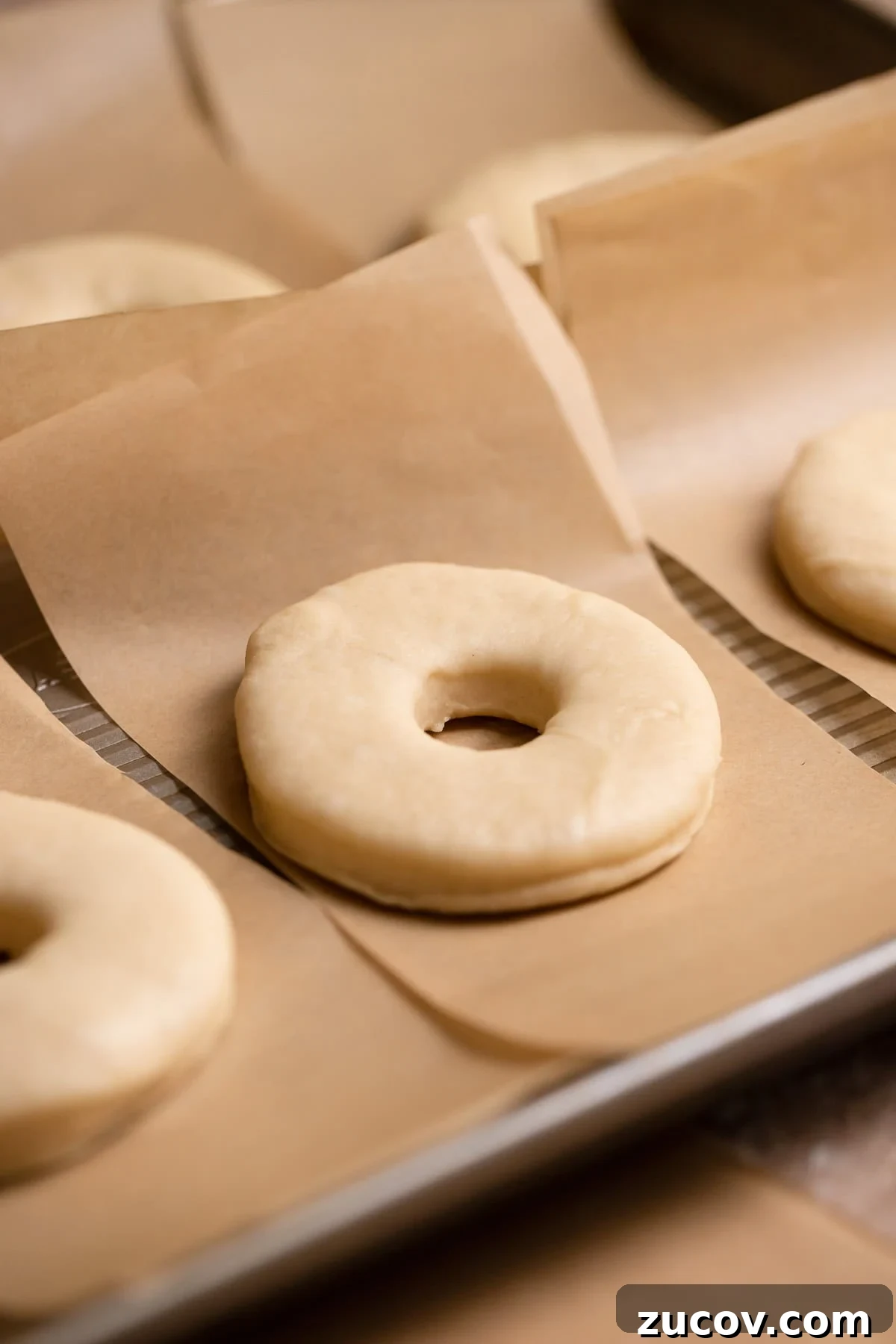 A cut donut on an individual square of parchment paper.