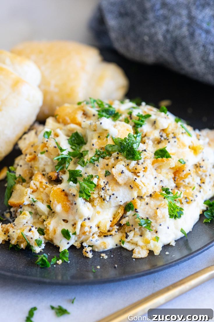 This poppy seed chicken is a classic, super creamy chicken casserole your family will love. You're going to want to put this one into your regular dinner rotation! #chickencasserole #poppyseedchicken poppy seed chicken with bread rolls on a plate