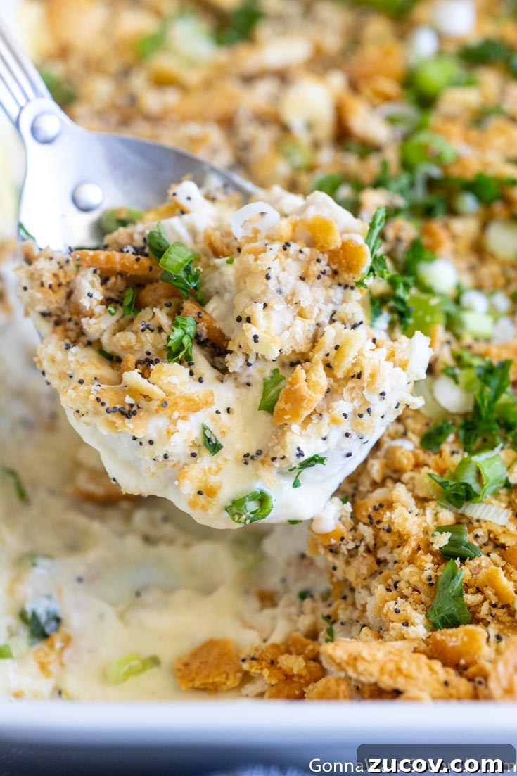 This poppy seed chicken is a classic, super creamy chicken casserole your family will love. You're going to want to put this one into your regular dinner rotation! #chickencasserole #poppyseedchicken scooping easy poppy seed chicken recipe from the casserole