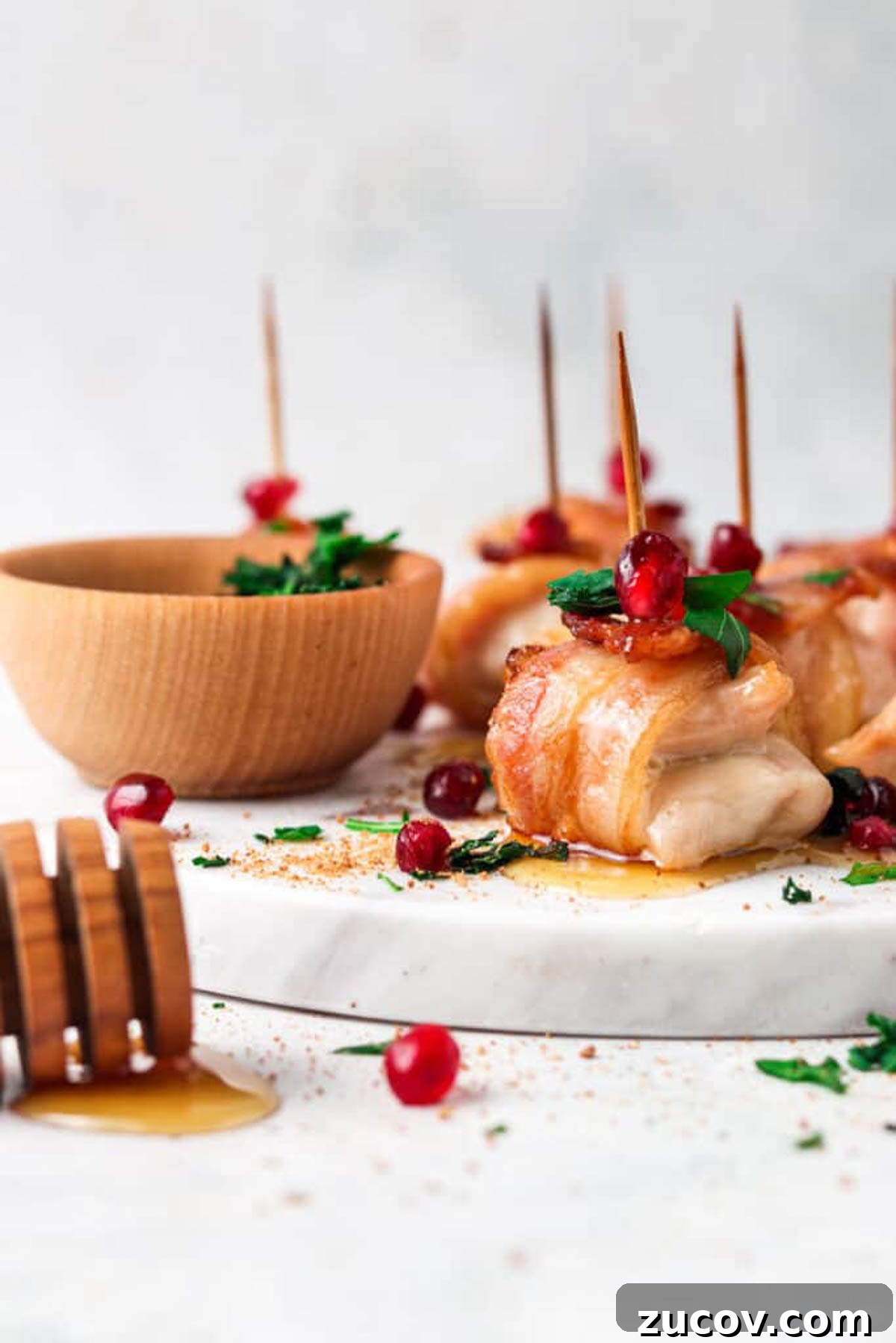 Crispy Bacon-Wrapped Chicken Bites with Maple Glaze 2 AIP bacon maple chicken bites on a marble board with maple honey drizzled.