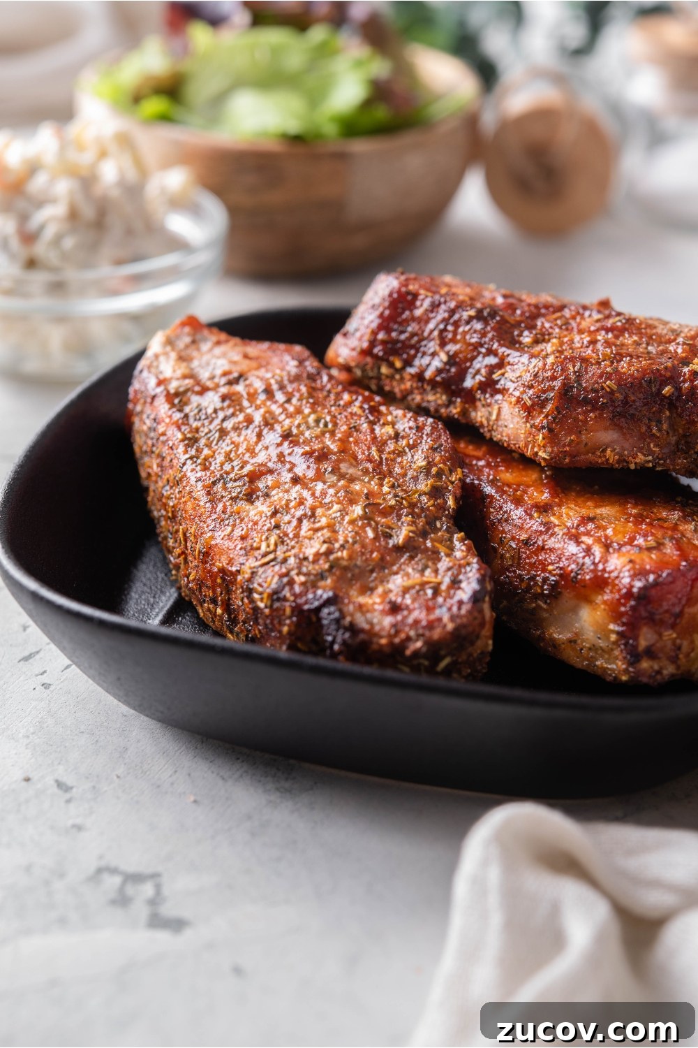 Oven-Baked Boneless Country-Style Pork Ribs — Juicy and Tender 7 A stack of three seasoned barbecue pork ribs on a black plate.