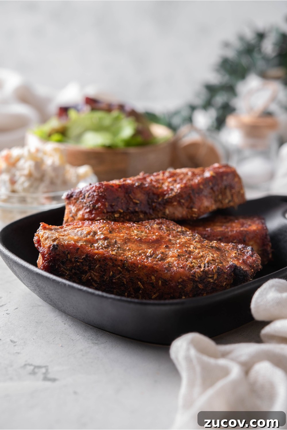 Oven-Baked Boneless Country-Style Pork Ribs — Juicy and Tender 8 A stack of seasoned boneless ribs on a black plate.